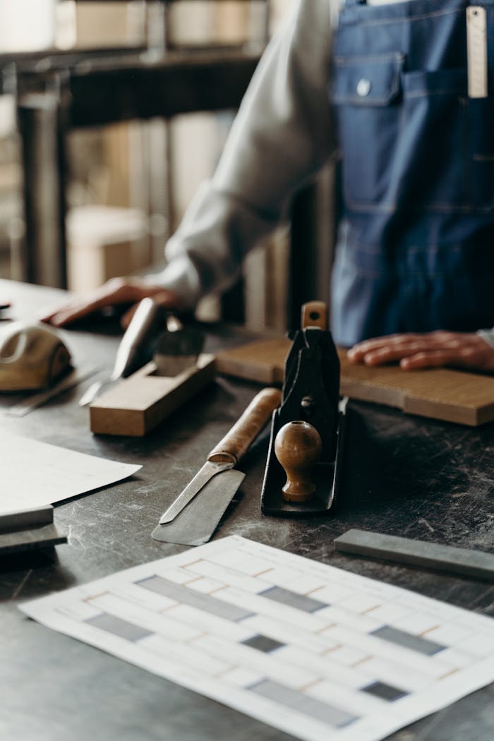 Person Holding a Plank Near Carving Tools